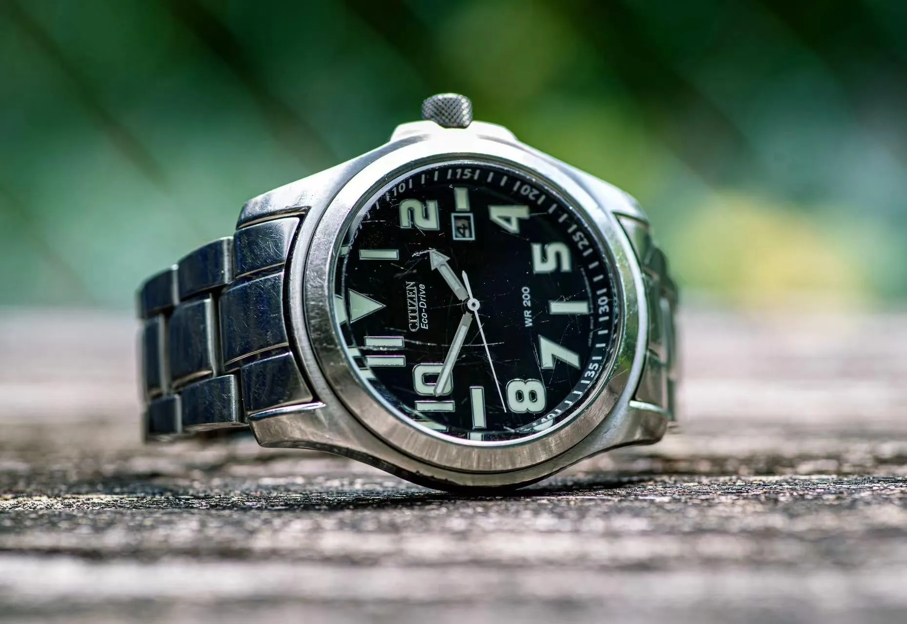 Citizen Eco-Drive with scratched mineral crystal, fine surface marks visible under raking light.