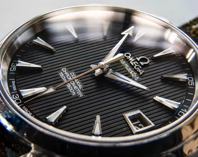 Omega Aqua Terra dial macro: polished applied baton indices gleaming on horizontal-stripe black dial.