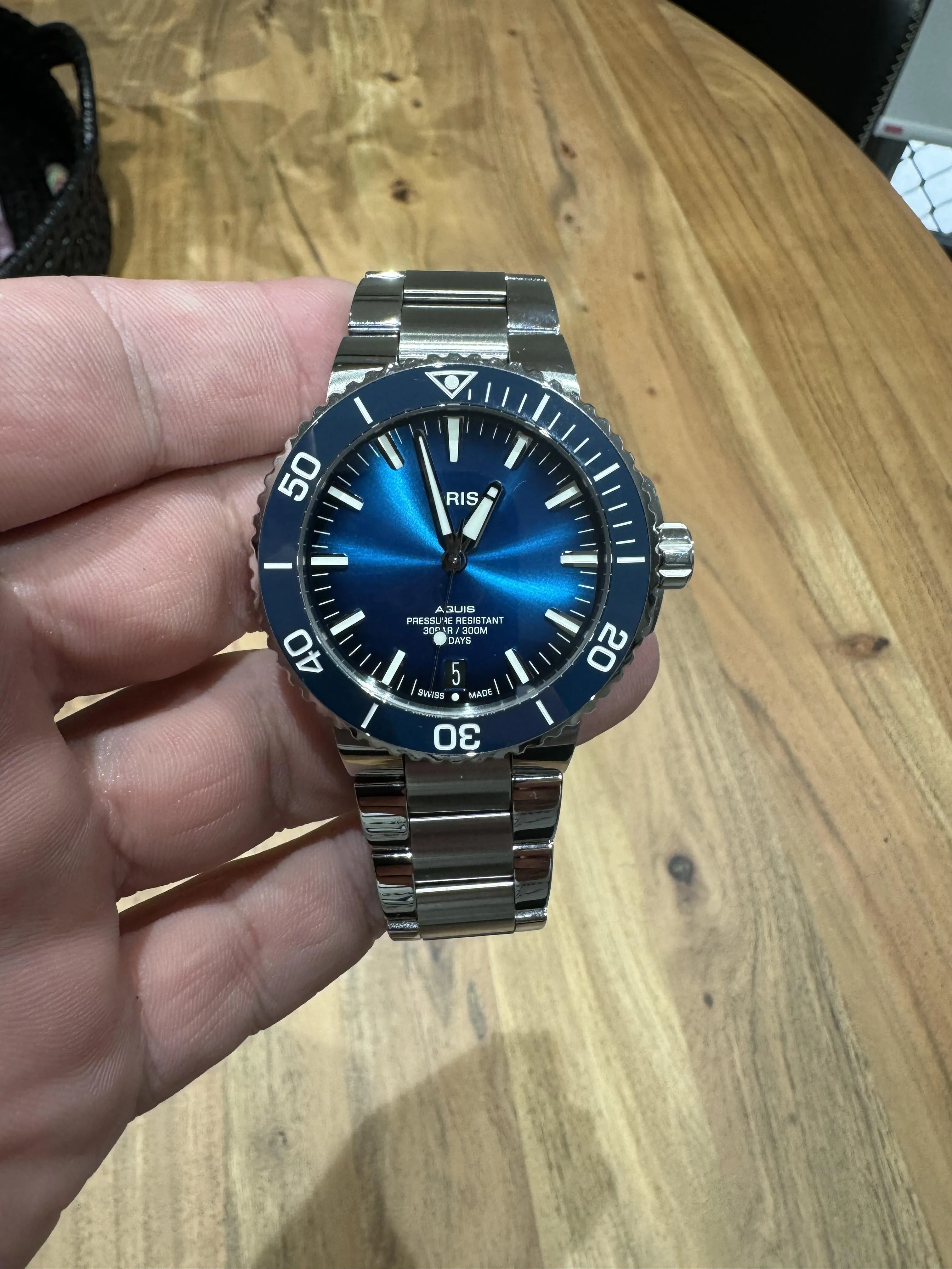 Oris Aquis blue sunburst dial, blue ceramic bezel, held in hand, front-on