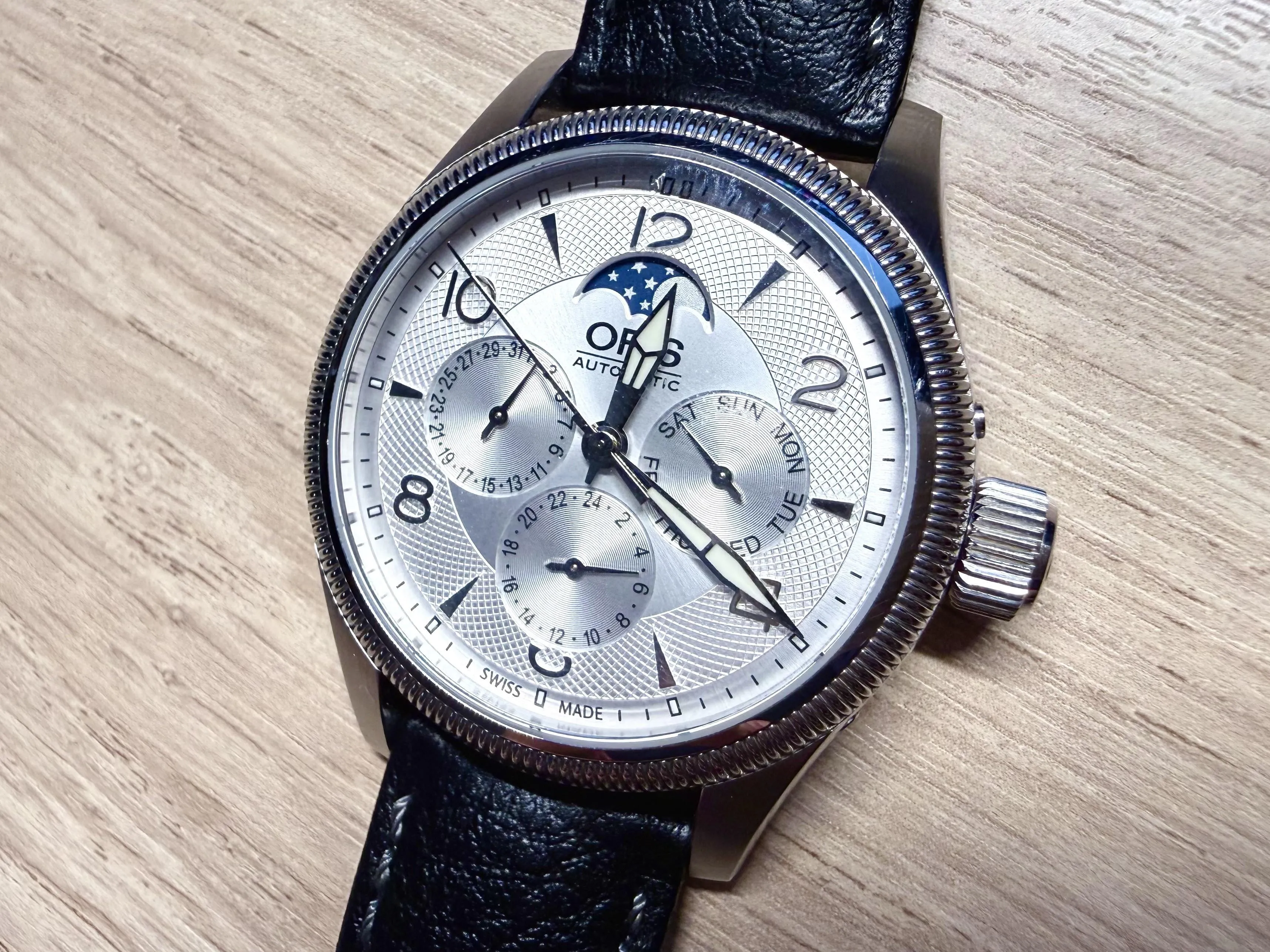 Oris Artelier Moonphase silver dial with Arabic numerals and blue moonphase, flat-lay