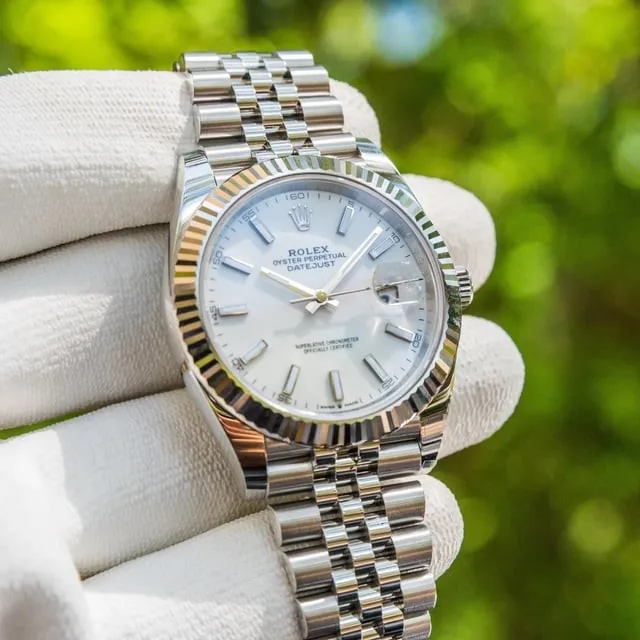 Rolex Datejust 41 white dial fluted bezel Jubilee bracelet held in gloved hand outdoors