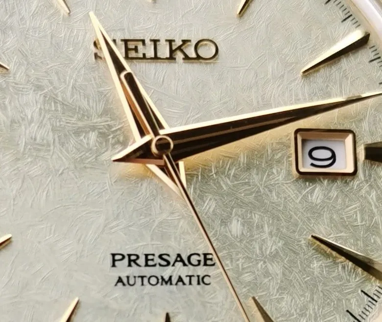 Close-up of Seiko Presage dial showing gold dauphine hands with centre ridge on textured silver dial