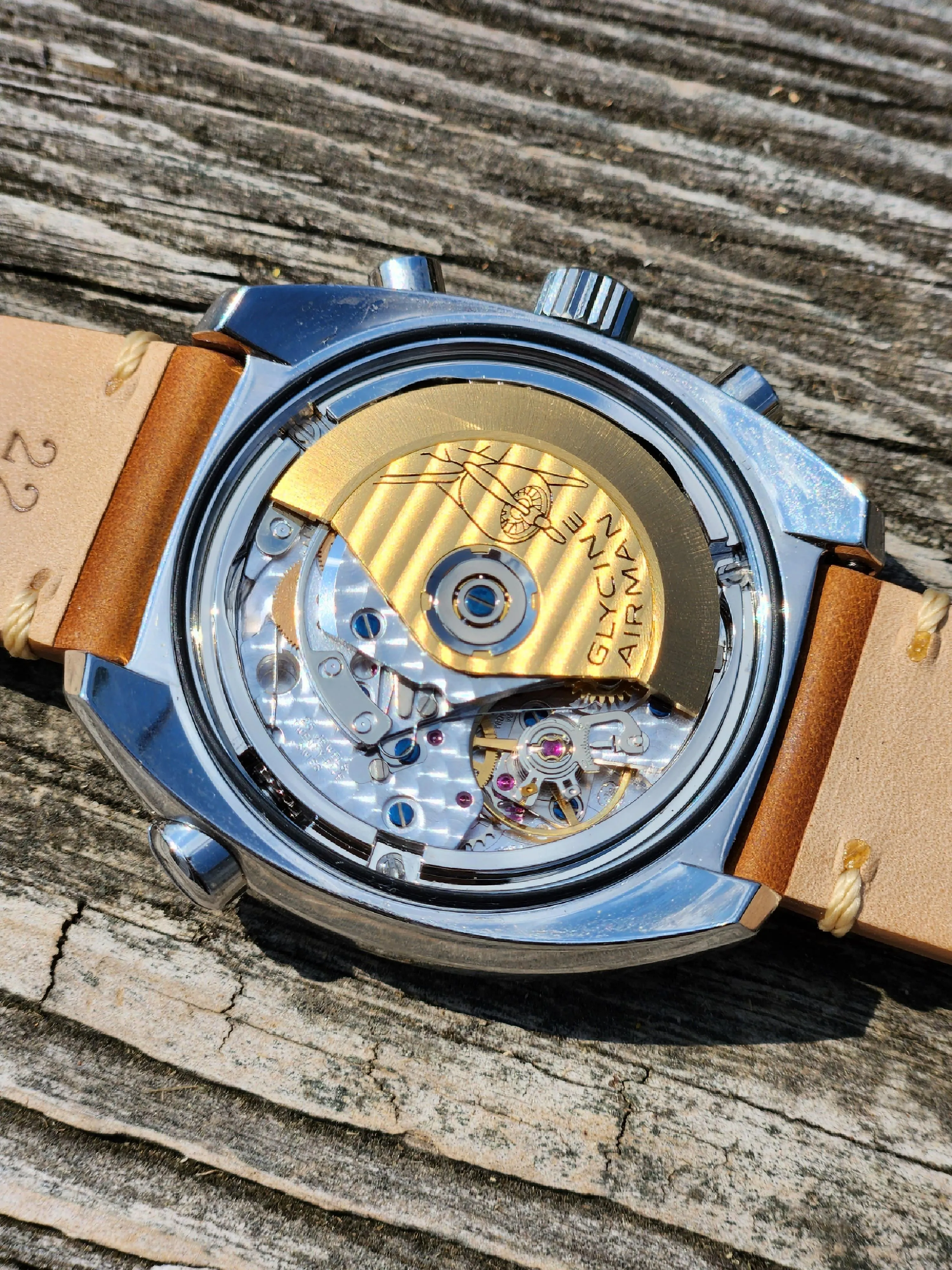Glycine Airman exhibition caseback showing gold rotor and Geneva-striped bridges