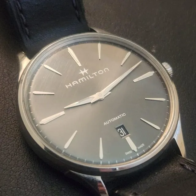 Hamilton Jazzmaster grey sunburst dial on black leather strap, flat lay on dark surface