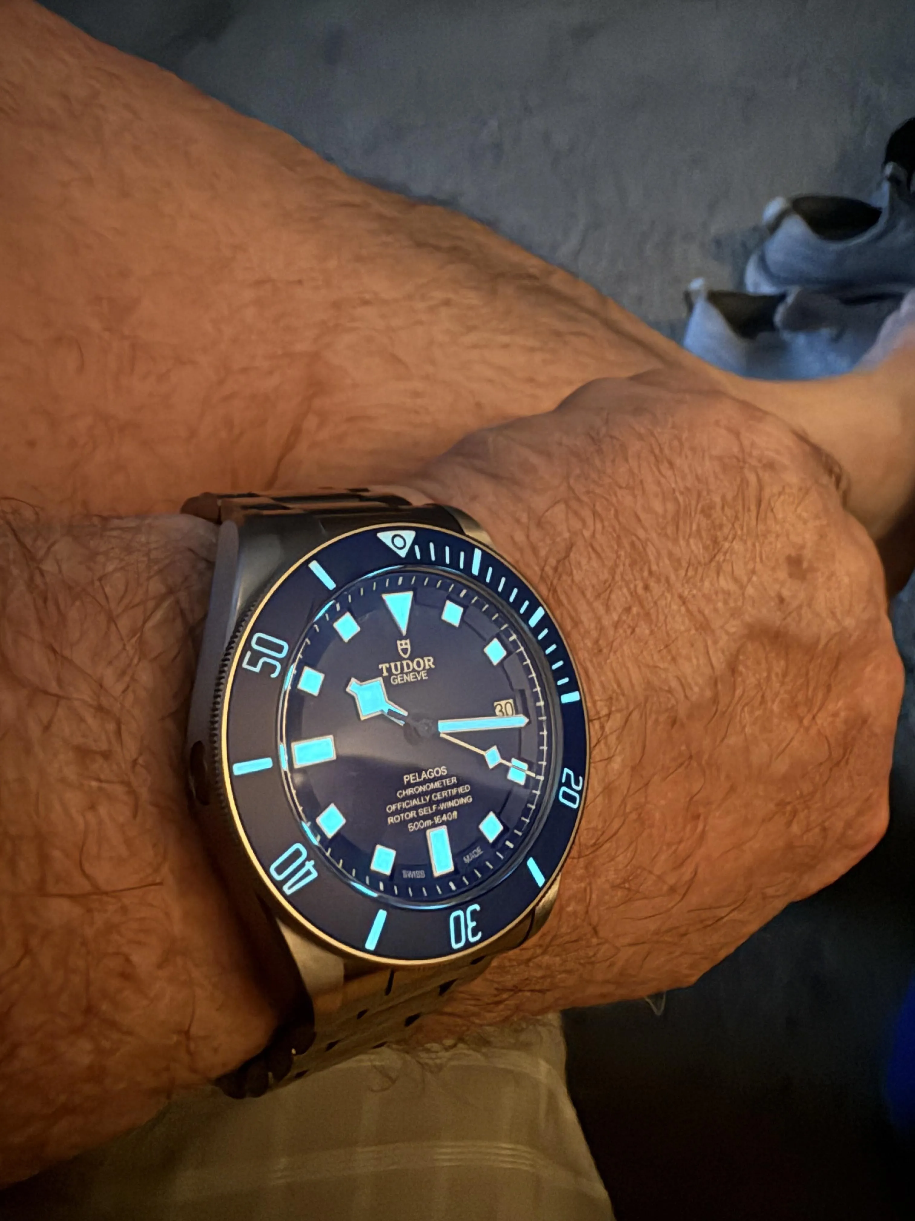 Tudor Pelagos blue dial with glowing cyan lume indices and hands in dim light