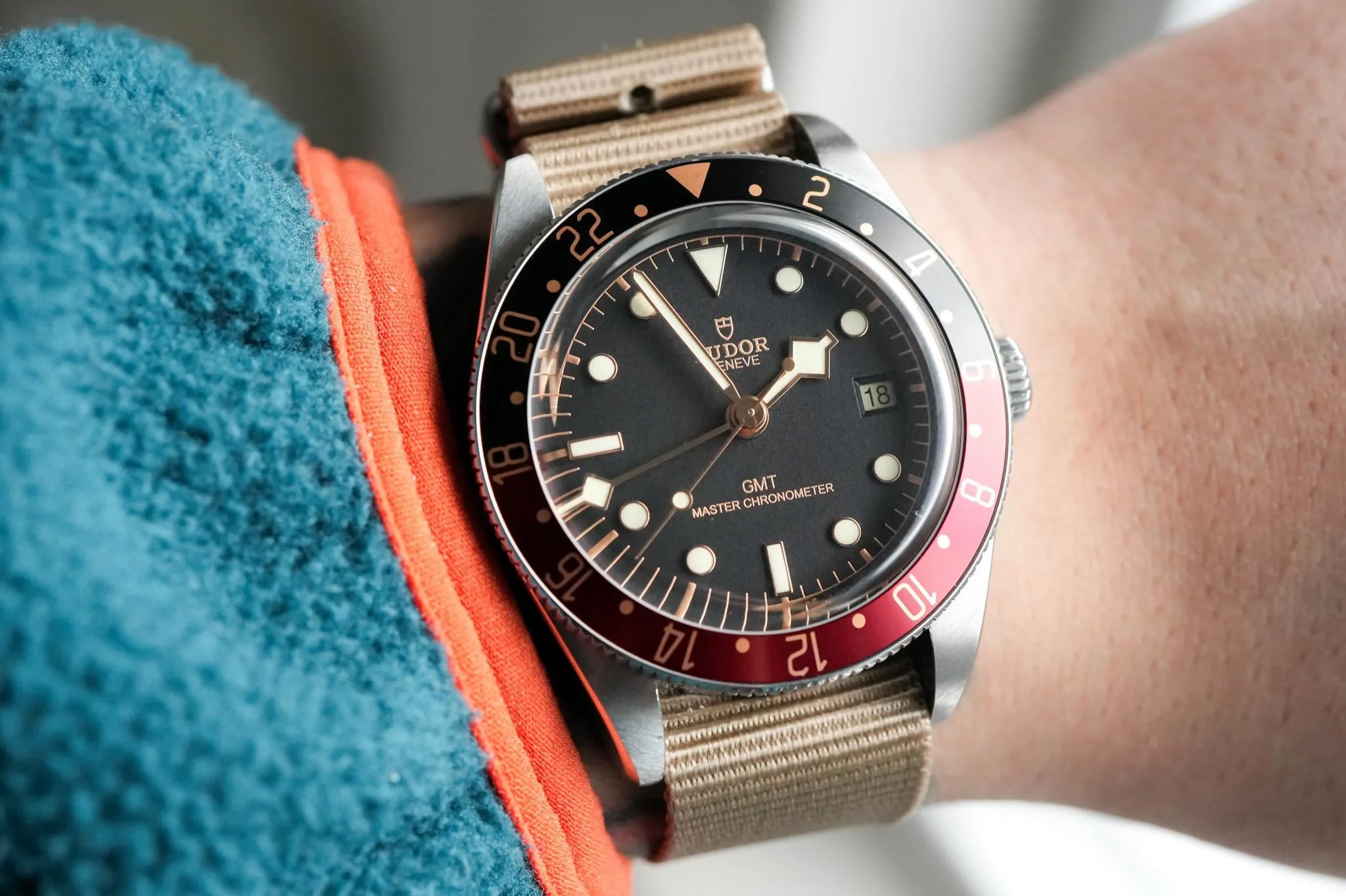 Tudor Black Bay GMT on tan NATO strap on wrist, black-burgundy bezel prominent