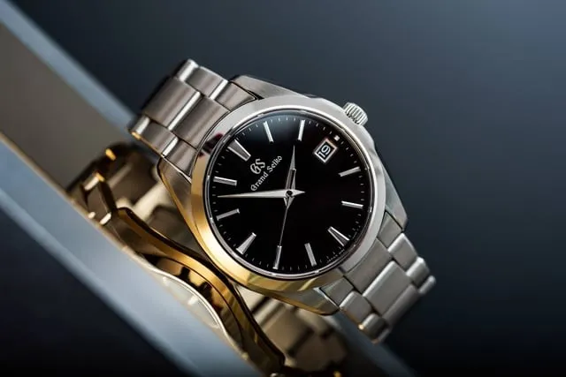 Grand Seiko black dial flat-lay showing polished case flanks and reflection
