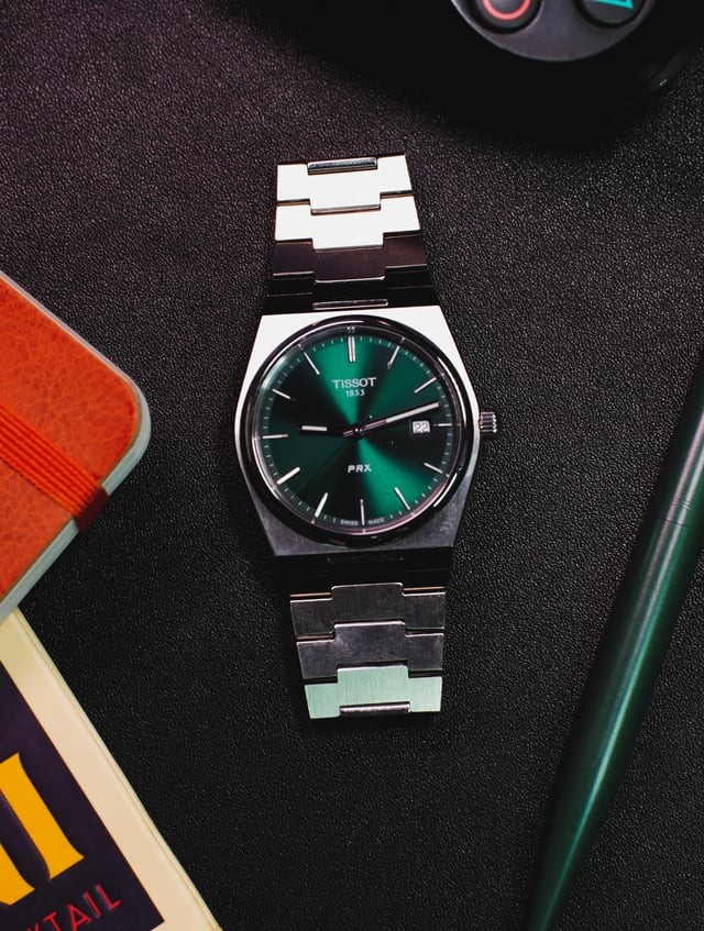 Tissot PRX quartz with green sunburst dial on dark surface