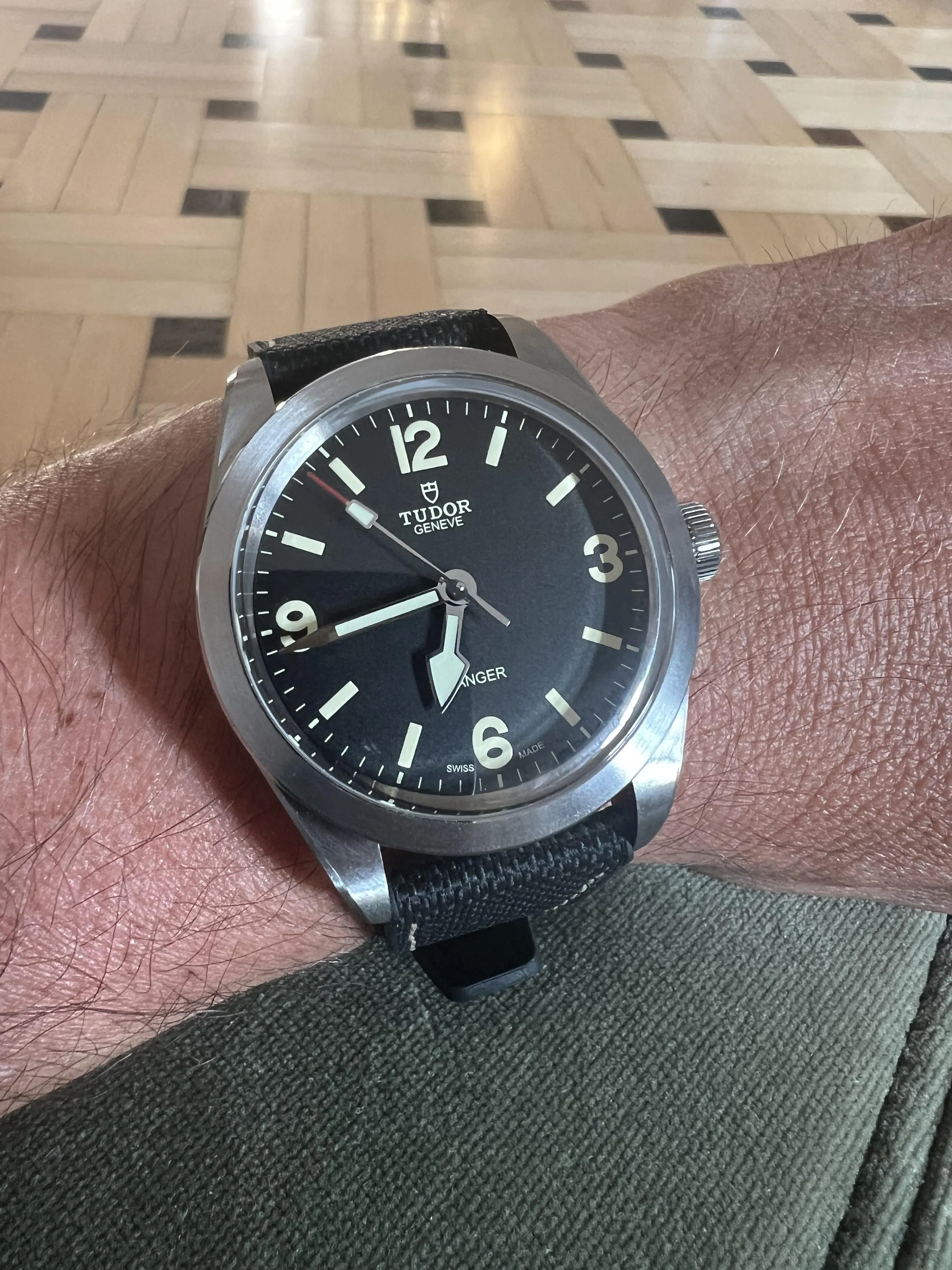 Tudor Ranger on wrist, black dial, canvas strap, parquet floor background