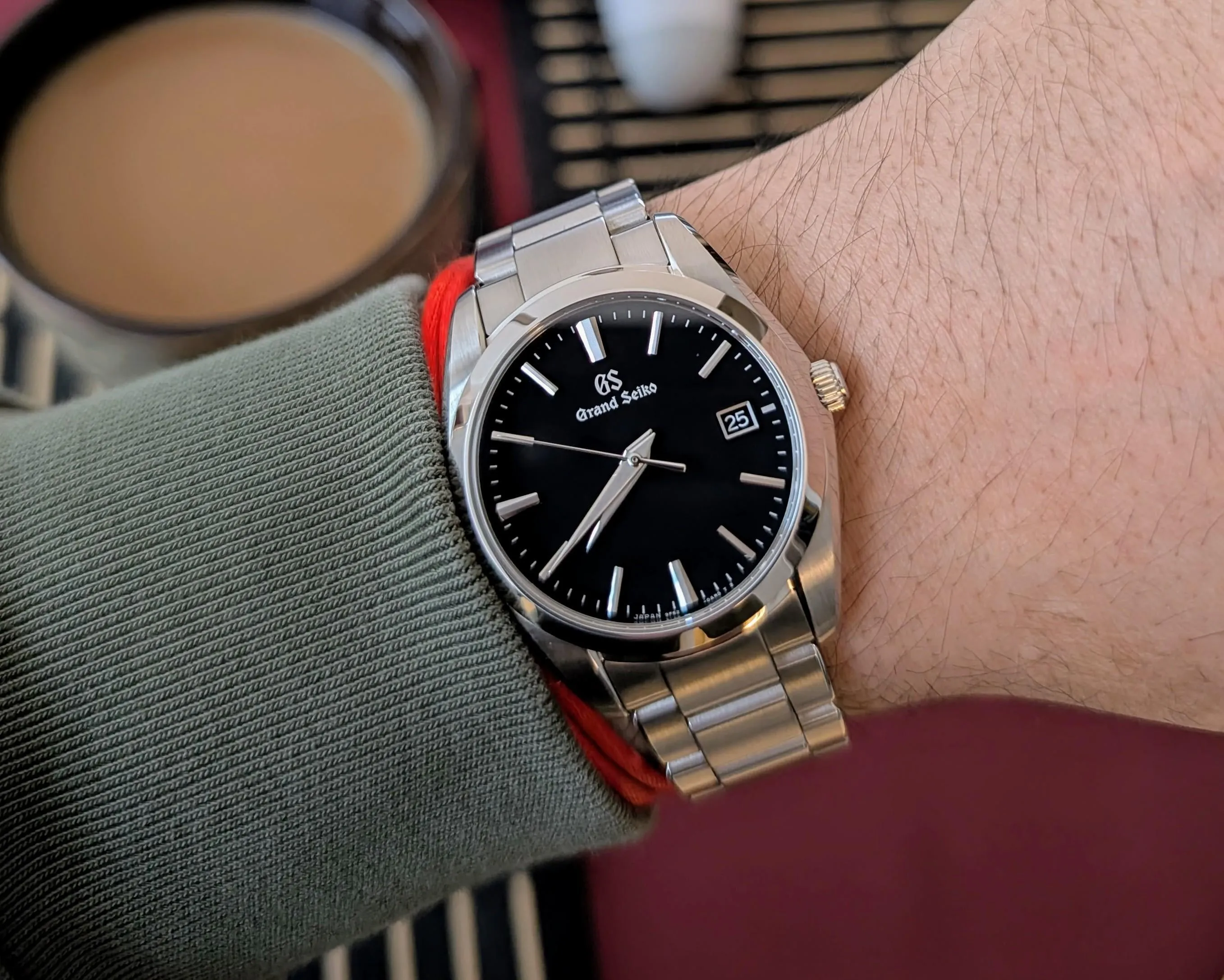 Grand Seiko SBGX261 on wrist, black dial, Zaratsu case bevels catching natural light.