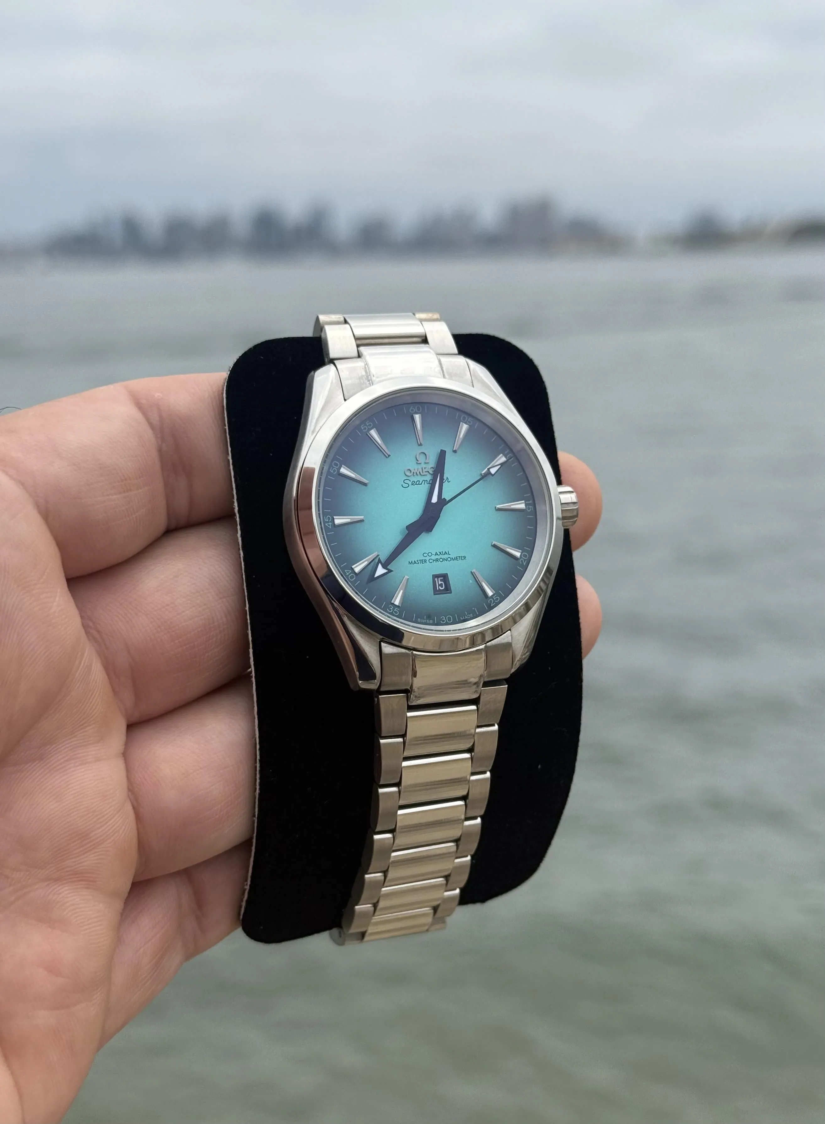 Omega Seamaster Aqua Terra ice-blue dial on steel bracelet held near waterfront