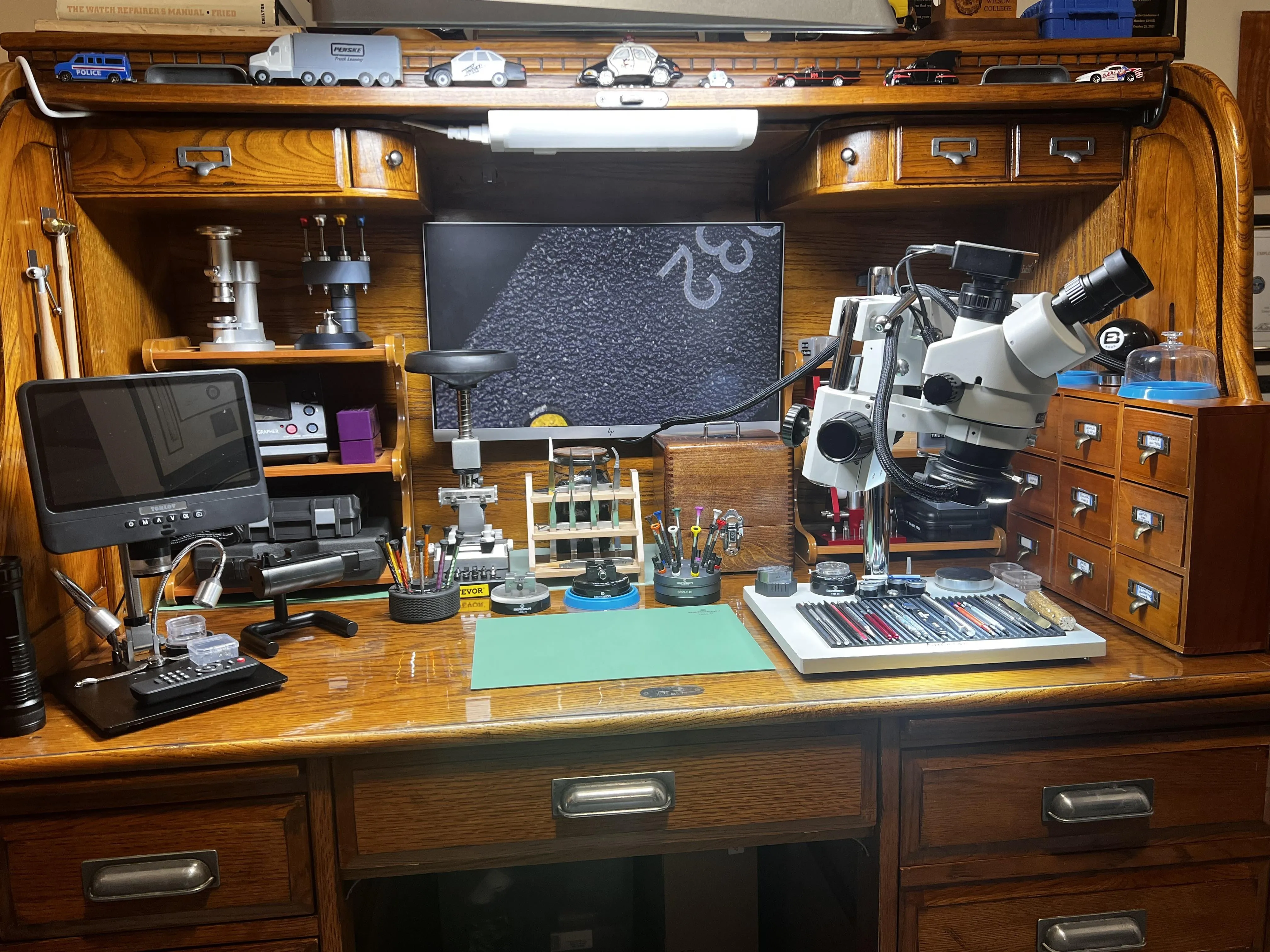 Watchmaker's roll-top desk workshop with microscope, timing machine, and tools