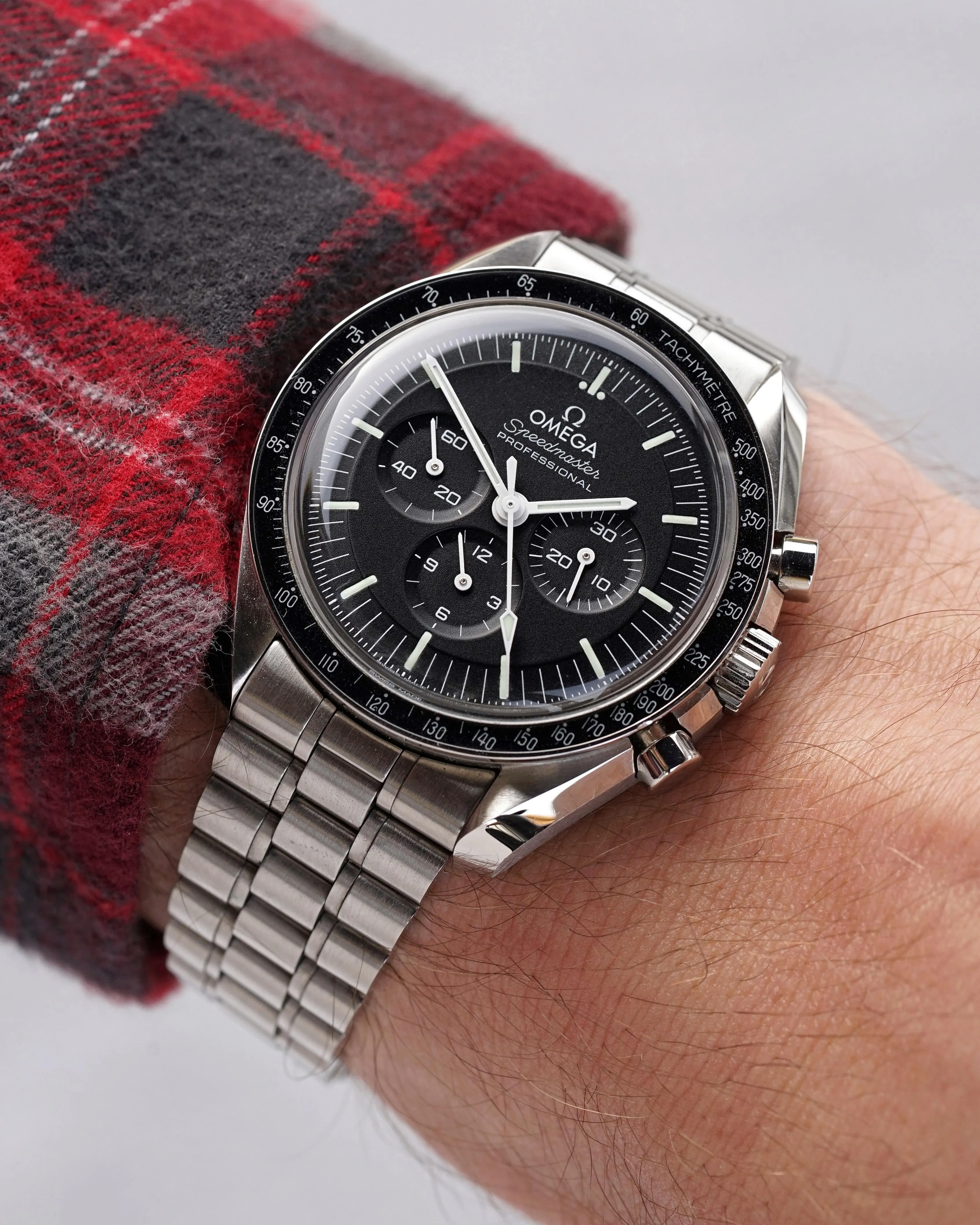 Omega Speedmaster Professional black dial on bracelet, wrist shot, plaid sleeve