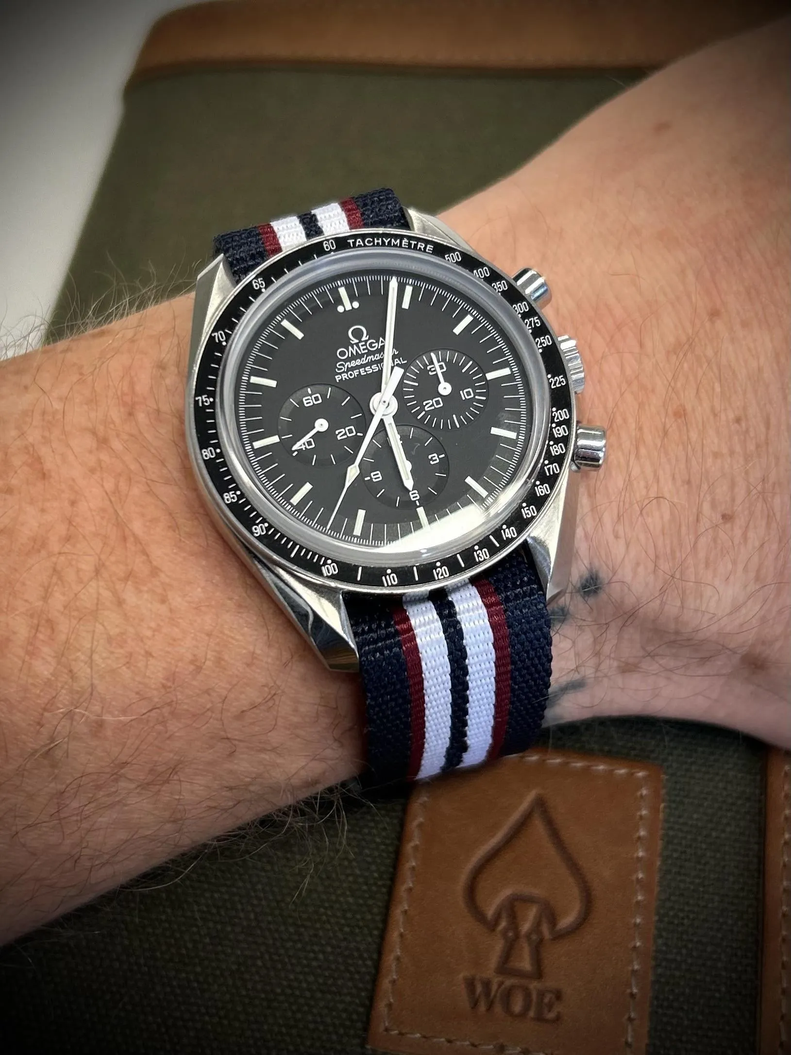 Omega Speedmaster Professional on wrist with navy/white/burgundy NATO strap