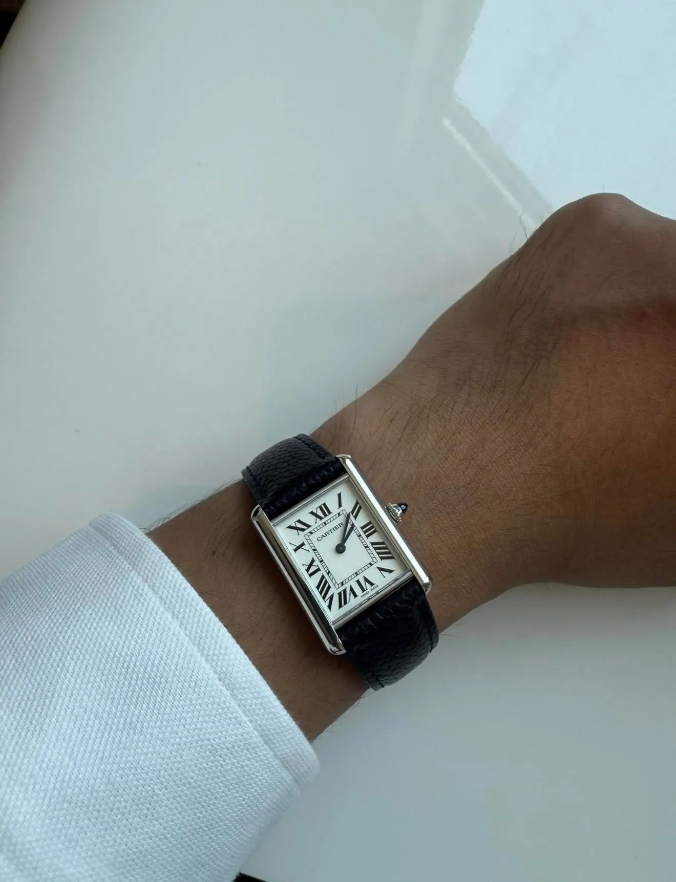 Cartier Tank Must large on black leather strap, front-on wrist shot, white background.